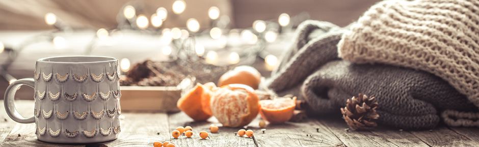 Cozy winter scene with mug of tea, warm sweaters and fruits