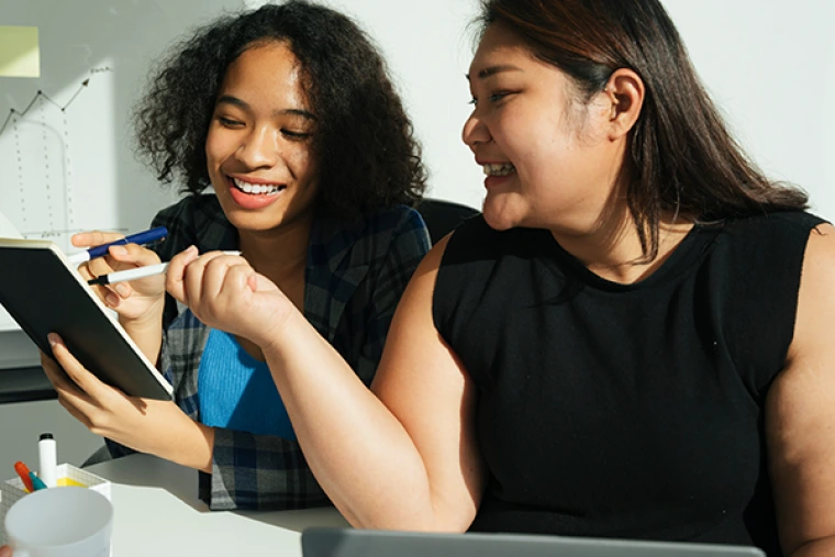 Two smiling women working in an office