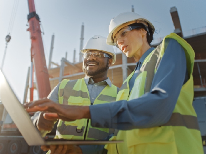 Two construction project managers discussing the project plan on site.