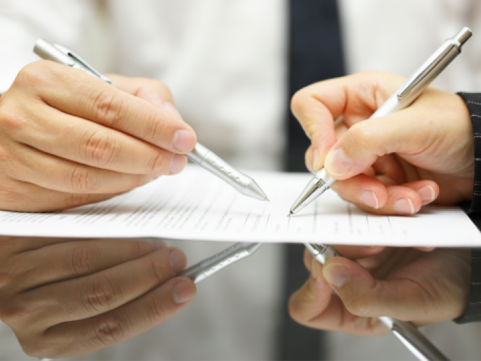 Spanish-English Business Translation Two hands signing business documents